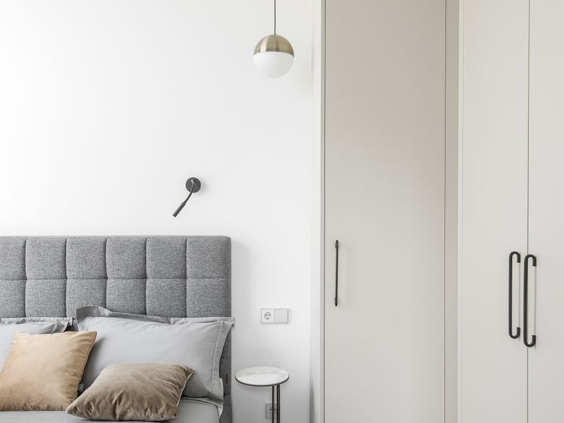 A modern, well-maintained bedroom featuring built-in floor-to-ceiling wardrobes, contemporary pendant lighting, and high-quality laminate flooring.