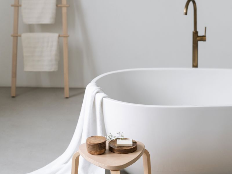A modern bathroom featuring a minimalist freestanding bathtub paired with an elegant brass floor-mounted faucet.