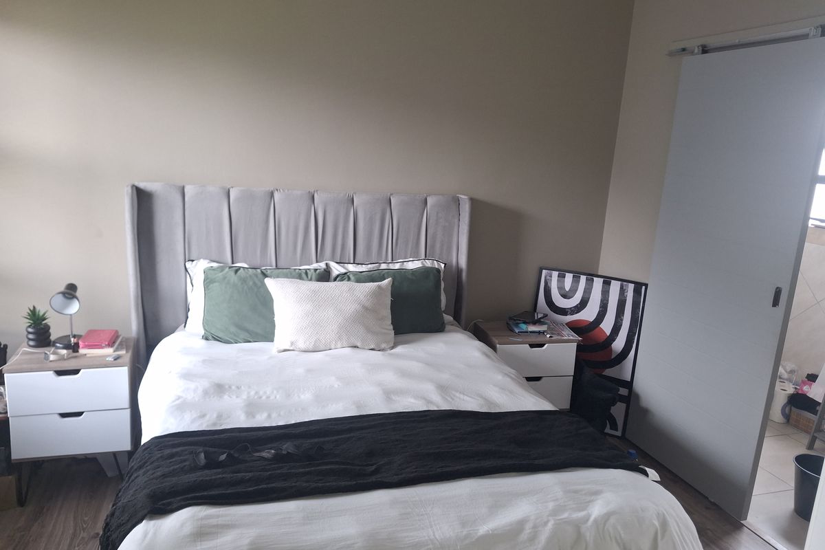 A well-maintained bedroom featuring modern laminate flooring and a functional sliding door entry.