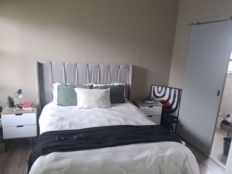 A well-maintained bedroom featuring modern laminate flooring and a functional sliding door entry.