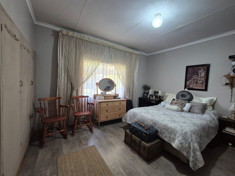 A well-proportioned bedroom featuring laminate flooring, neutral wall finishes, and built-in cupboards providing ample storage space.