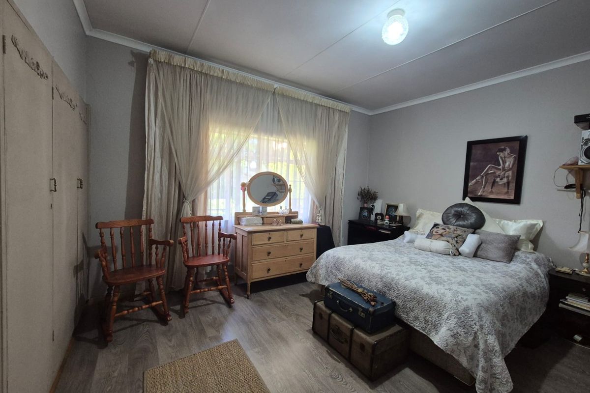 A well-proportioned bedroom featuring laminate flooring, neutral wall finishes, and built-in cupboards providing ample storage space.