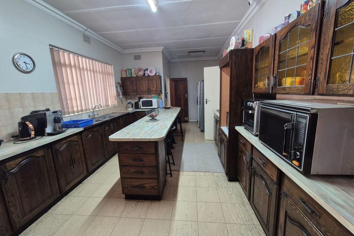 Spacious kitchen featuring extensive wooden cabinetry, a central island with breakfast bar seating, and functional tiled flooring.