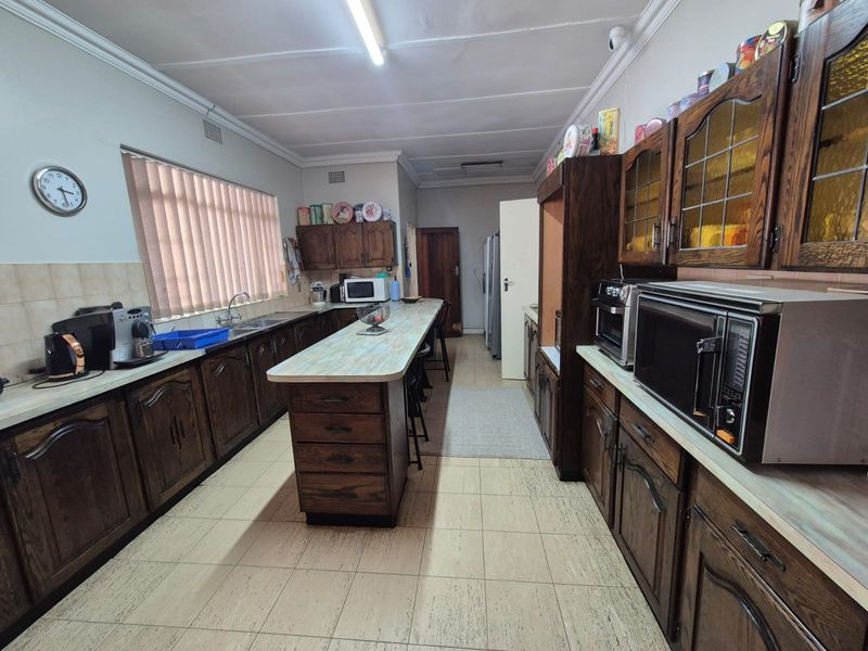 Spacious kitchen featuring extensive wooden cabinetry, a central island with breakfast bar seating, and functional tiled flooring.
