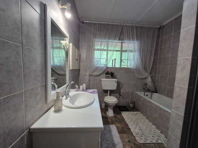 A functional bathroom featuring a vanity with a basin, a standard toilet, and a bathtub, finished with neutral wall and floor tiling.