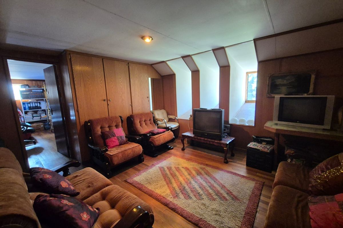 A living room featuring extensive wood paneling, built-in cabinetry, and recessed dormer windows, offering a dated aesthetic with potential for modernization.
