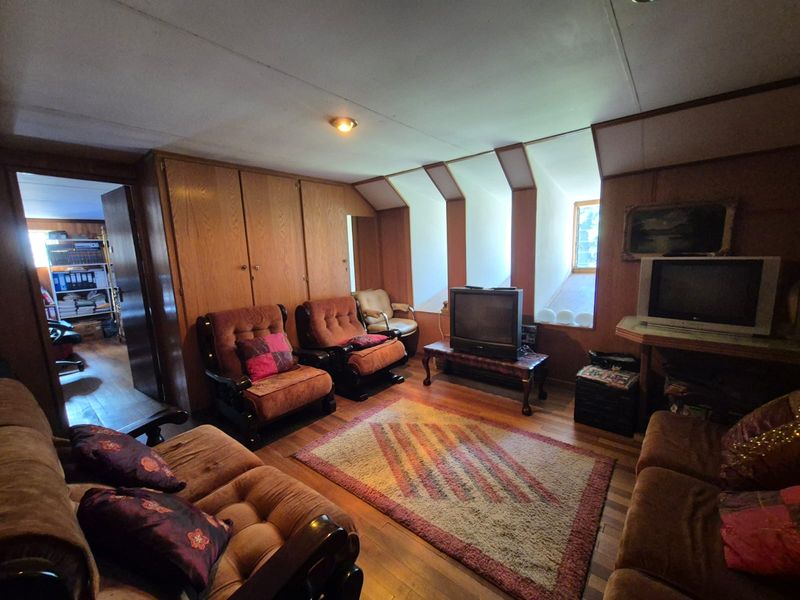 A living room featuring extensive wood paneling, built-in cabinetry, and recessed dormer windows, offering a dated aesthetic with potential for modernization.