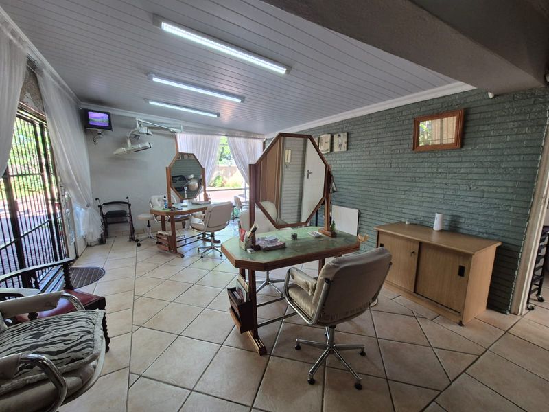 A versatile utility space featuring tiled flooring, a painted brick feature wall, and tongue and groove ceiling panels with integrated lighting.