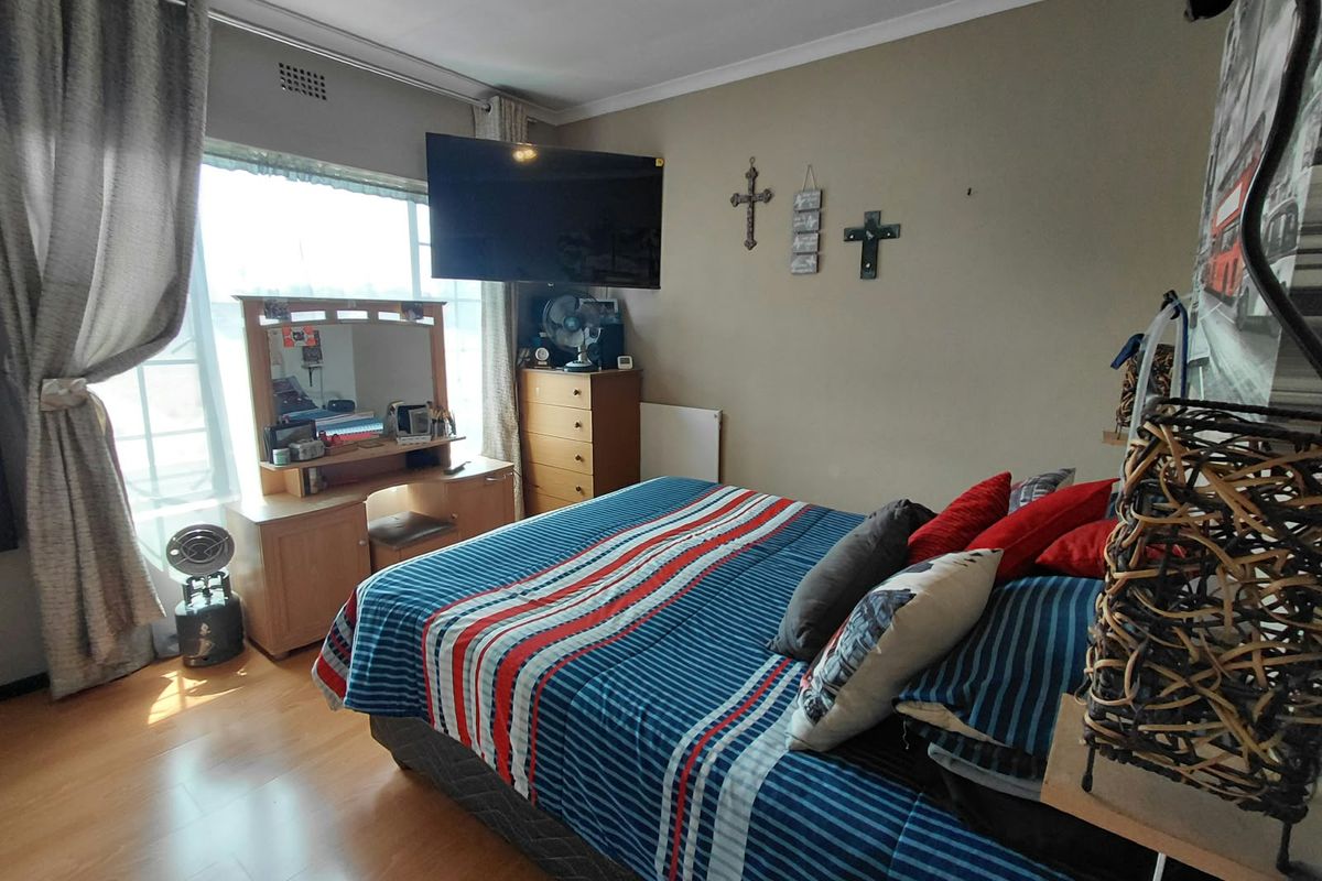 A bedroom featuring laminate flooring, coving, and a wall-mounted television bracket, offering a functional space with natural light from the window.