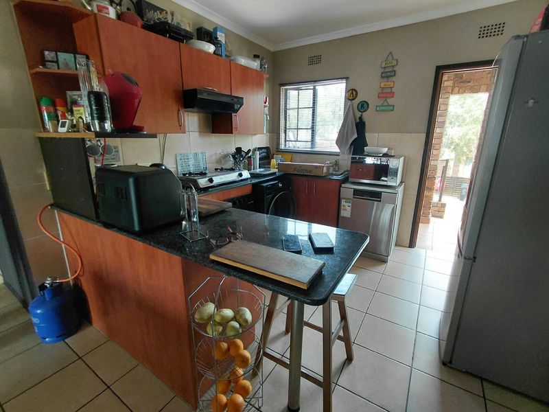 A functional kitchen featuring laminate cabinetry, granite countertops, a gas hob, and tiled flooring, with direct access to an outdoor area.