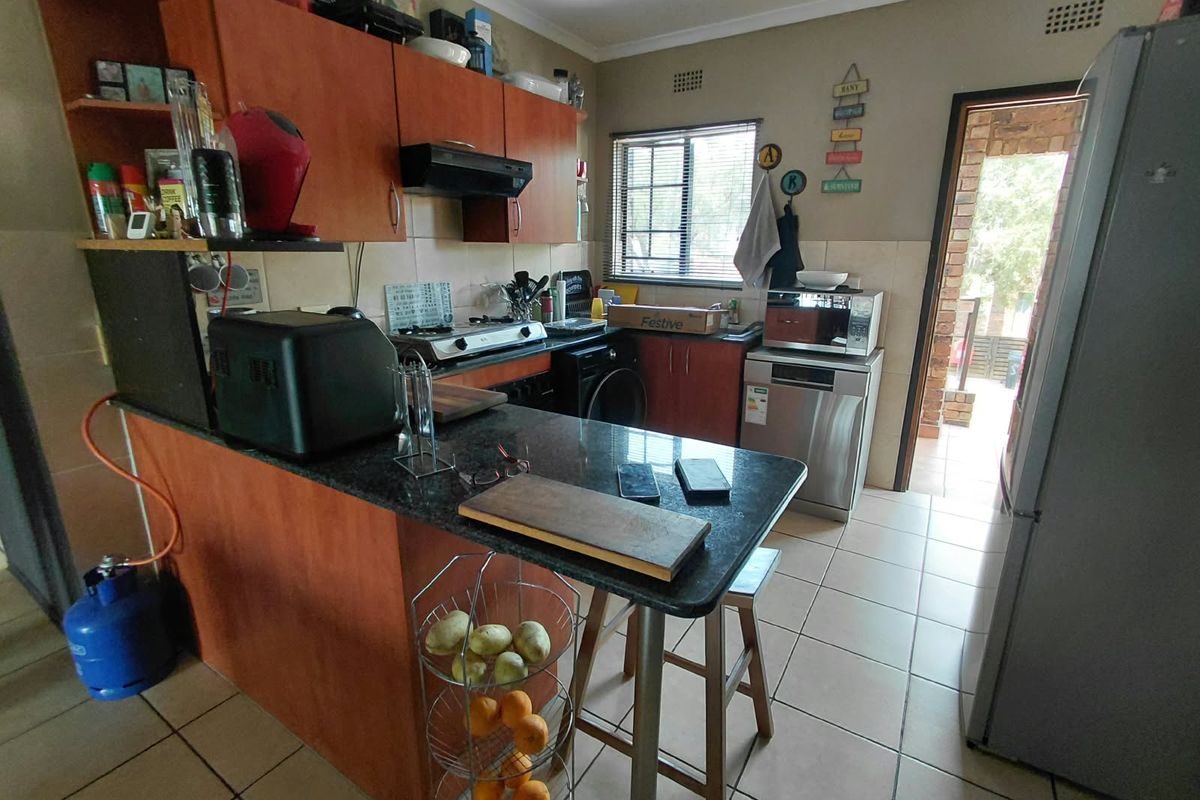 A functional kitchen featuring laminate cabinetry, granite countertops, a gas hob, and tiled flooring, with direct access to an outdoor area.