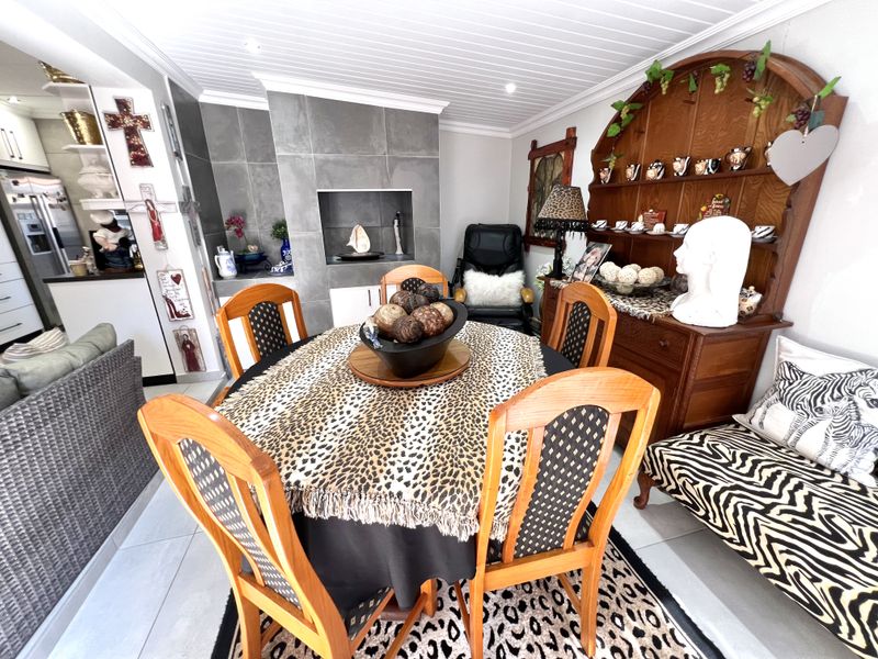 Open plan dining area featuring a built-in fireplace with grey tile surround, tiled flooring, and a white tongue and groove ceiling.