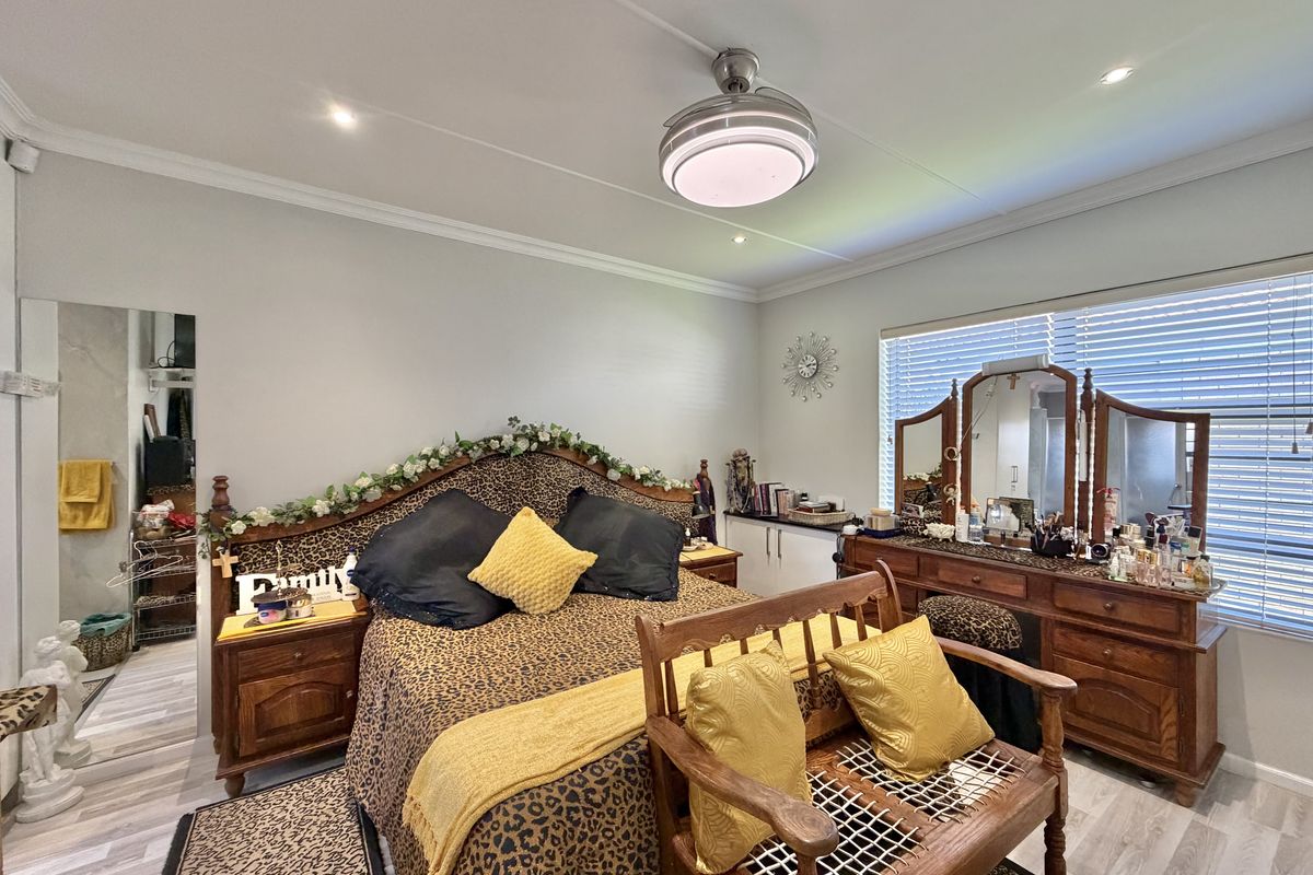 A well-maintained bedroom featuring recessed lighting, a ceiling fan, laminate flooring, and built-in cabinetry with venetian blinds.