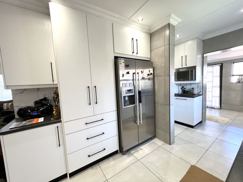 Modern kitchen featuring white built-in cabinetry, tiled flooring, and integrated appliances, with a clean, contemporary aesthetic and functional layout.