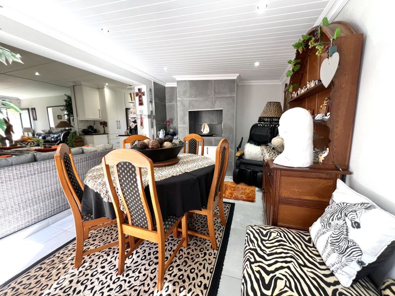 Open plan living and dining area featuring a built-in fireplace with tiled surround, tongue and groove ceiling, and neutral tiled flooring.