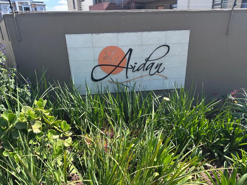 A clear view of the St. Aidan estate signage mounted on a boundary wall, surrounded by established garden landscaping.