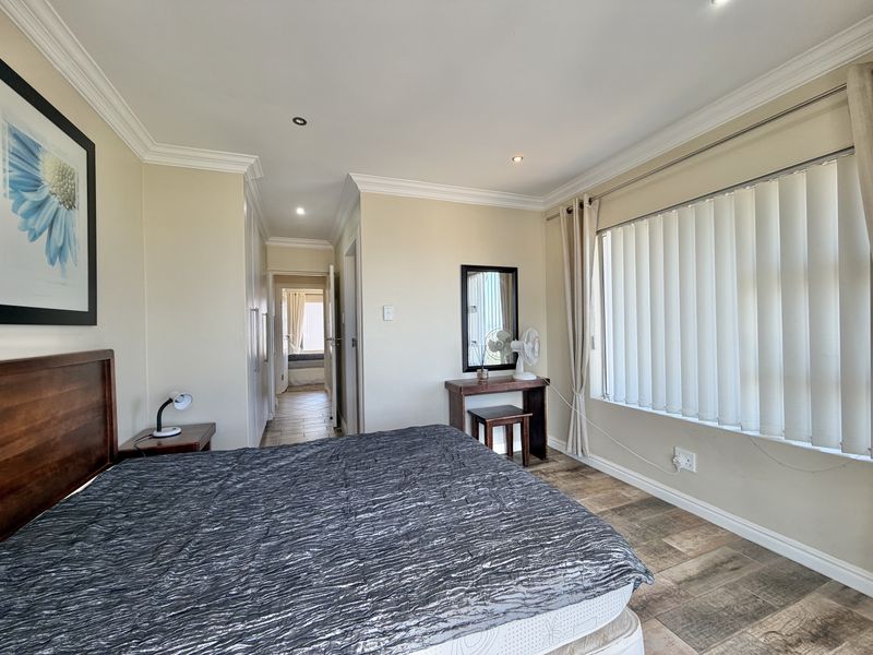 A well-maintained bedroom featuring tiled flooring, built-in cupboards, and vertical blinds, with a neutral color palette and recessed lighting.