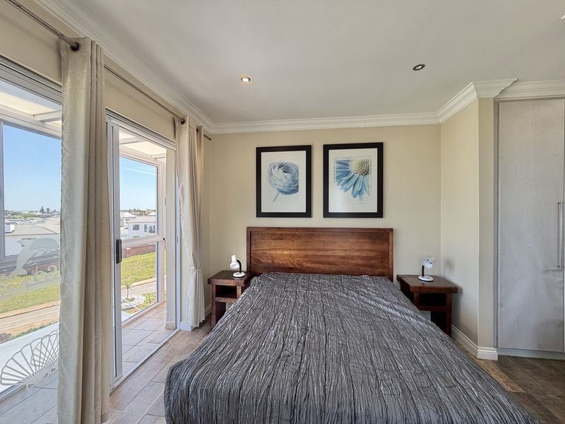 A well-maintained bedroom featuring tiled flooring, recessed lighting, crown molding, and a sliding glass door providing access to a balcony with neighborhood views.