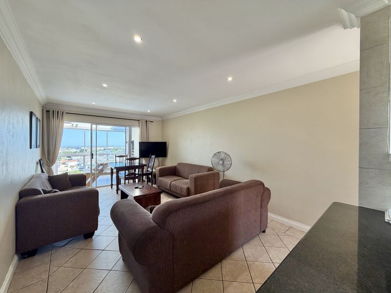 Open plan living area featuring tiled flooring, recessed lighting, and a sliding glass door leading to a balcony with city views.