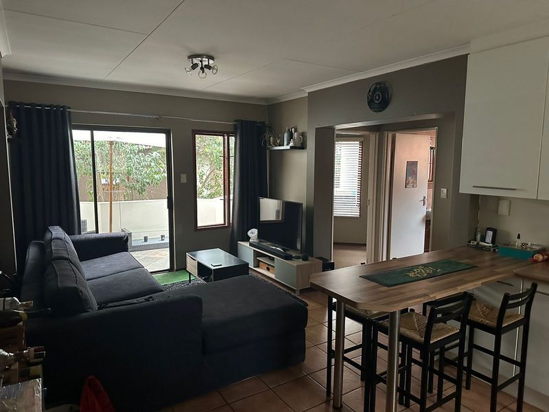 Open plan living and dining area featuring tiled flooring, a breakfast bar, and direct access to an outdoor patio through sliding glass doors.