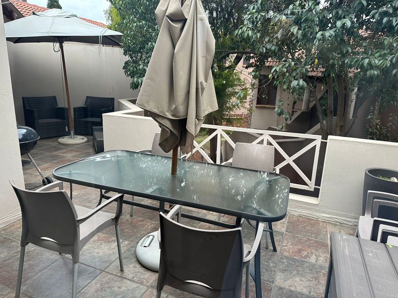 A private outdoor patio area featuring tiled flooring and a protective balustrade, providing a functional space for outdoor dining and relaxation.