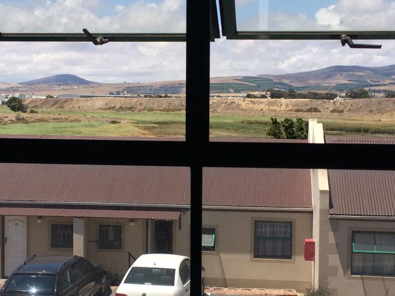 A view from an interior window looking out over a residential complex towards a rural landscape and distant hills.