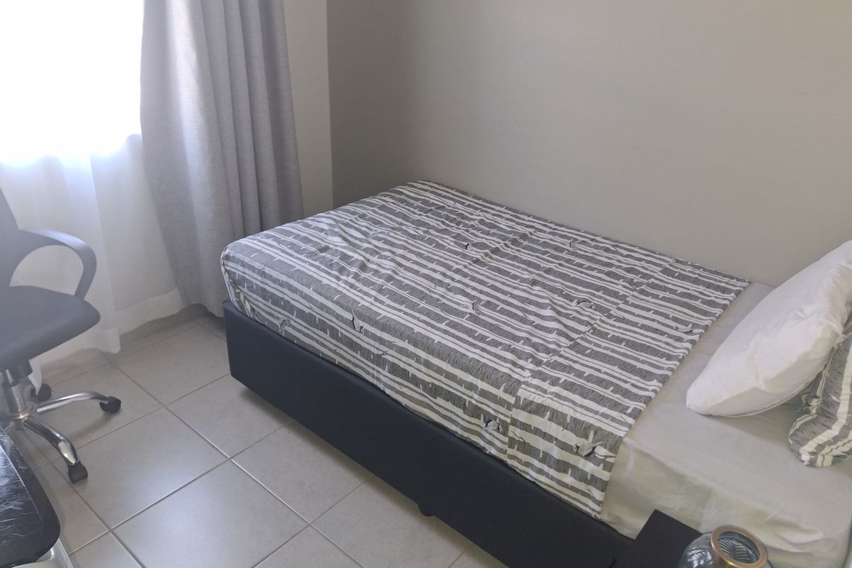 A functional bedroom featuring neutral wall tones and tiled flooring, providing a clean and simple space.