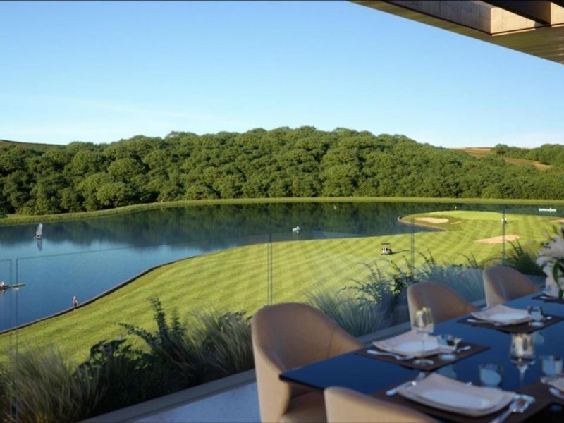 Stunning elevated view overlooking a manicured golf course, lake, and lush green landscape from a modern covered patio area.