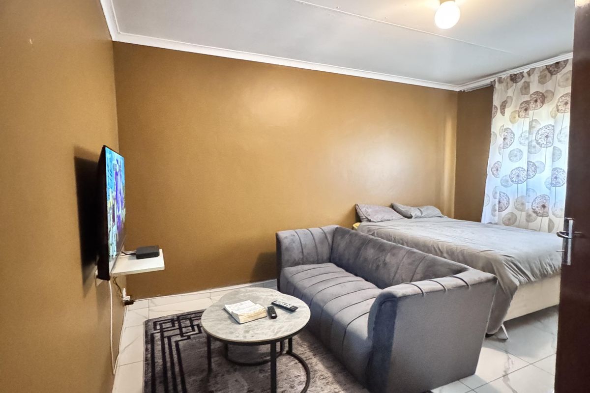 A compact bedroom featuring tiled flooring and neutral wall finishes, providing a functional living space.