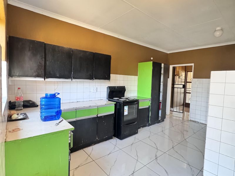 Kitchen featuring tiled flooring, a tiled backsplash, and built-in cabinetry with a freestanding stove.