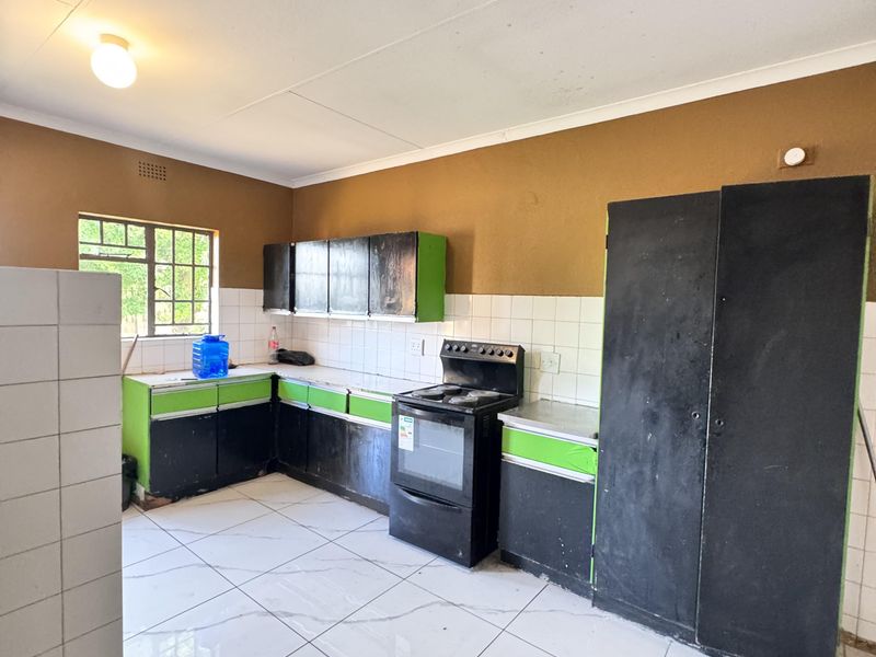 A functional kitchen space featuring tiled flooring, a tiled backsplash, and built-in cabinetry with a freestanding stove.