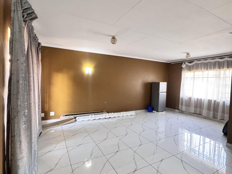 A spacious, empty living room featuring polished marble-look floor tiles and neutral wall finishes, offering a blank canvas for interior design.