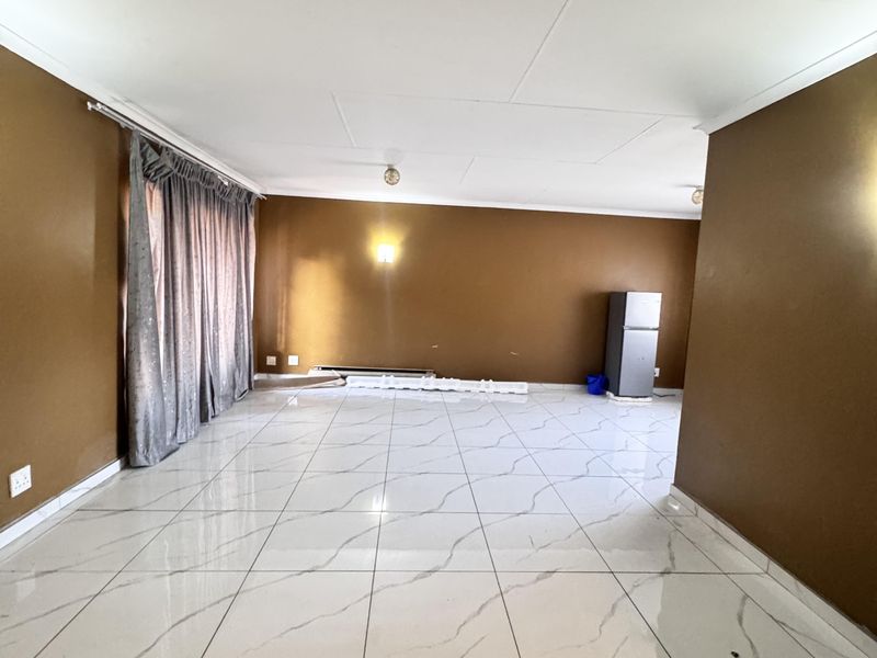 Spacious living area featuring polished marble-look floor tiles and neutral brown walls, offering a blank canvas for interior design and furniture placement.