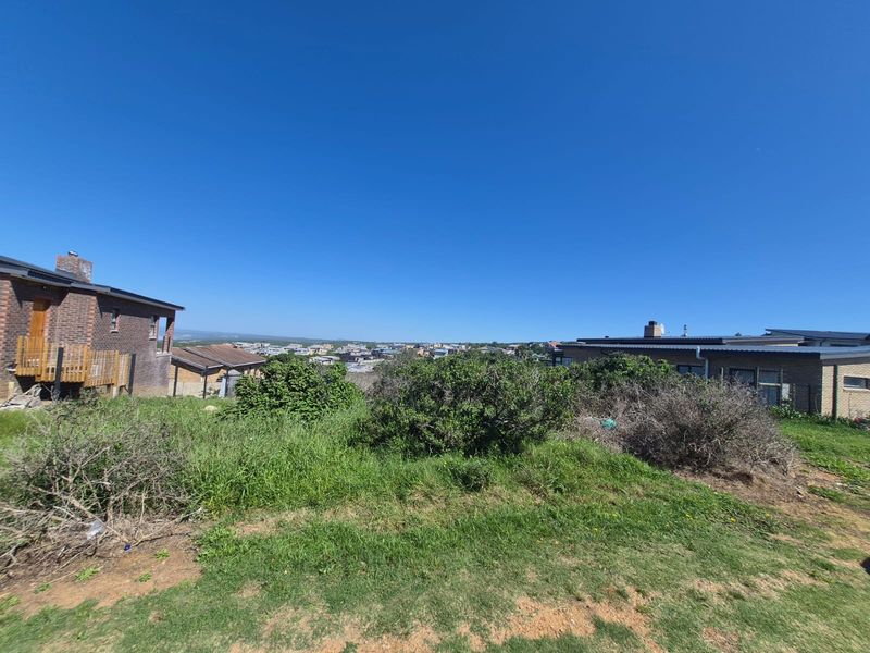 A wide-angle view of the residential land plot, showcasing the natural slope, existing vegetation, and surrounding neighborhood context.