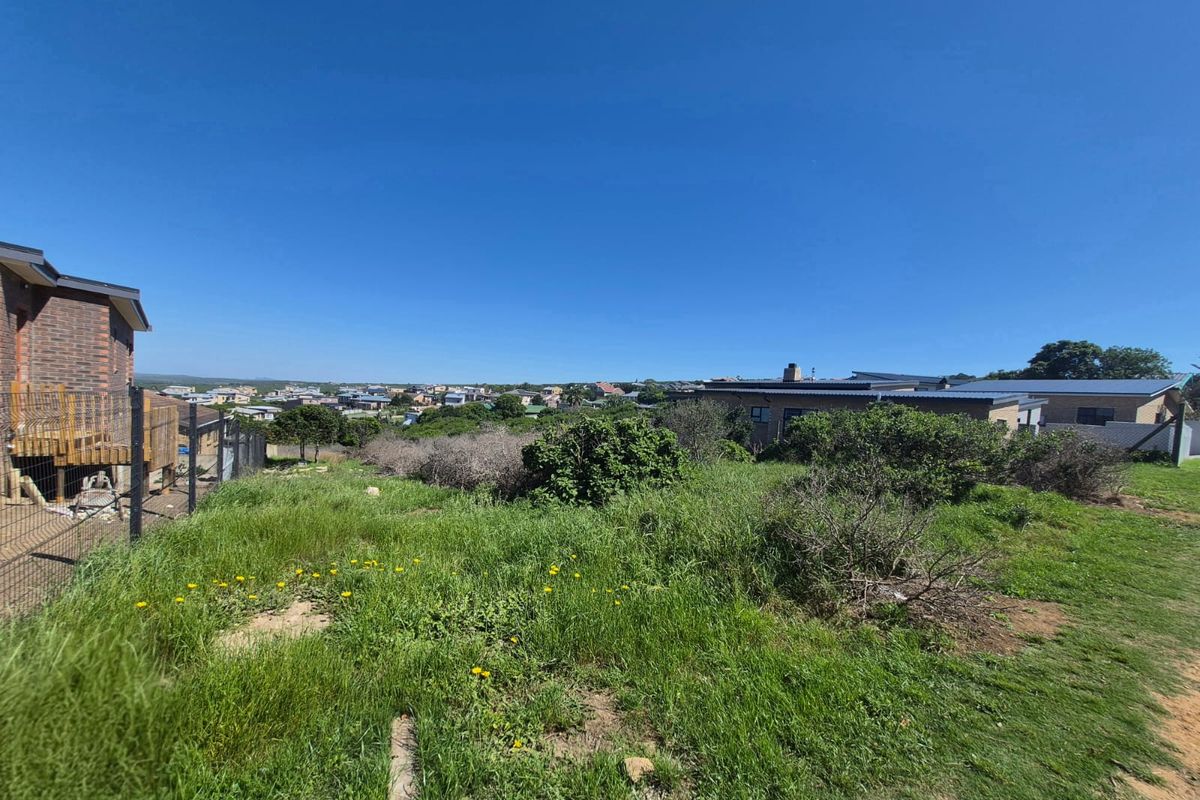 A view of the rear portion of the residential vacant land, featuring natural vegetation and surrounding neighborhood properties.