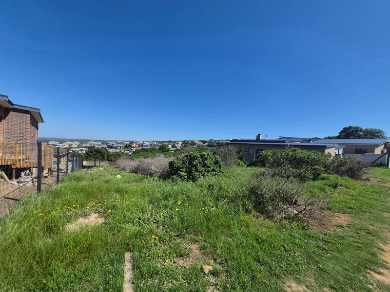 A view of the rear portion of the residential vacant land, featuring natural vegetation and surrounding neighborhood properties.