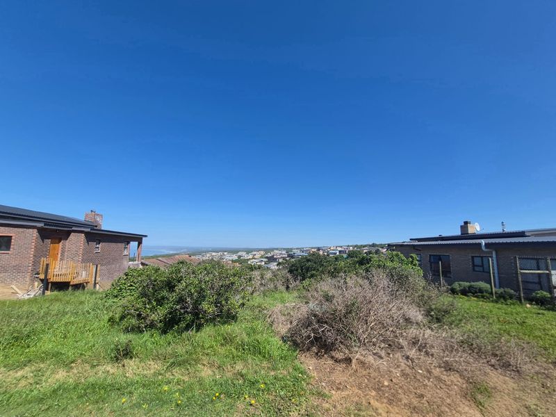 A scenic view overlooking a residential neighborhood and coastal landscape, captured from the vacant land property.