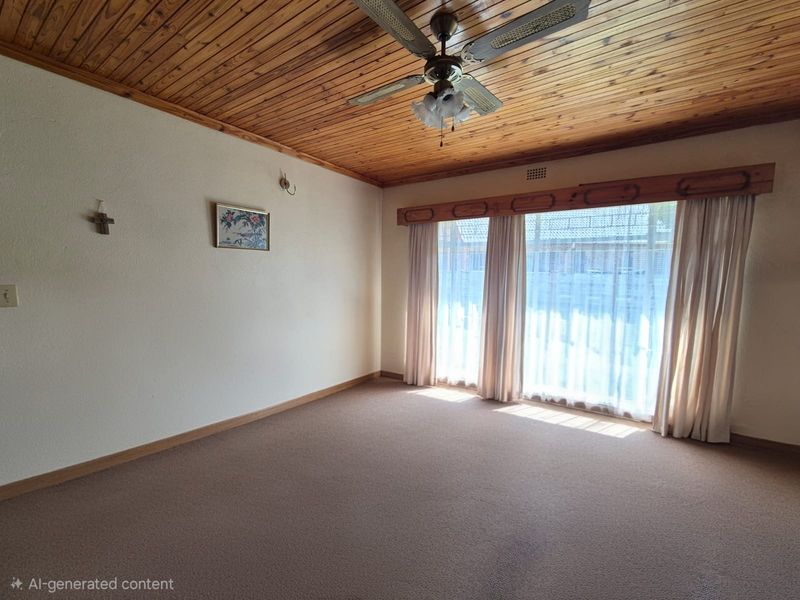 Spacious living room featuring a warm timber tongue and groove ceiling, ceiling fan, and large windows allowing for ample natural light.