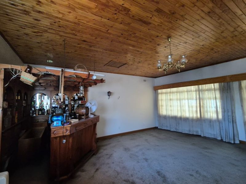 A dated bar area featuring a built-in wooden counter, traditional tongue and groove timber ceiling, and carpeted flooring.