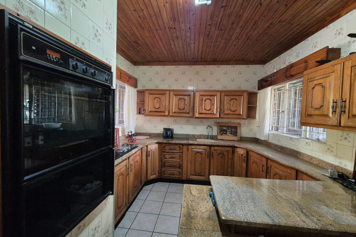A traditional kitchen featuring wooden cabinetry, granite countertops, and a timber ceiling, offering a classic aesthetic with potential for modern updates.