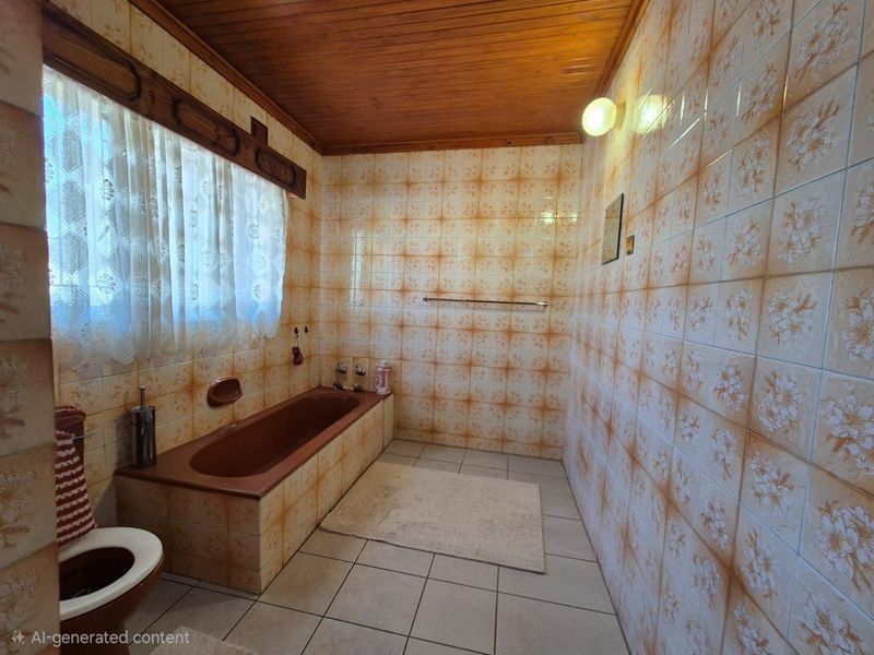 A dated bathroom featuring a built-in bathtub, patterned wall tiles, and a timber ceiling, offering significant potential for a modern renovation.