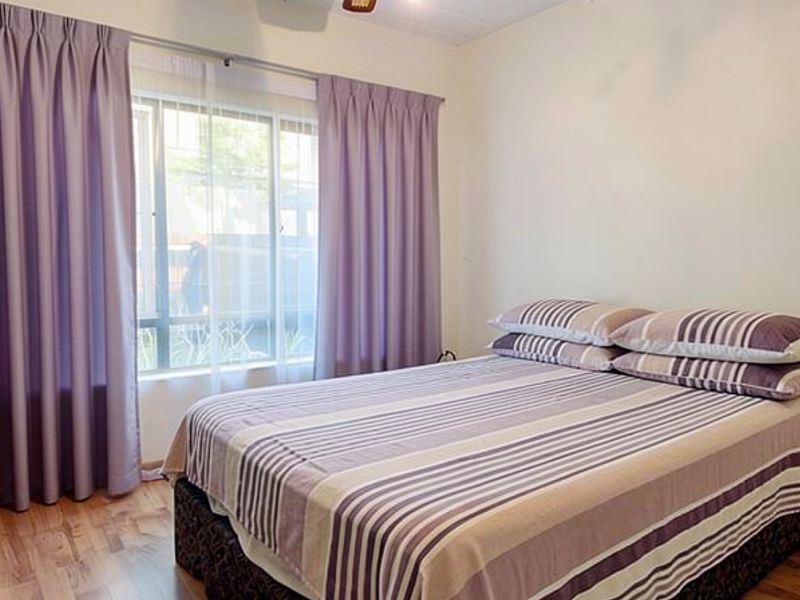 A functional bedroom featuring laminate flooring, a ceiling fan, and a built-in cupboard, providing a comfortable and practical living space.