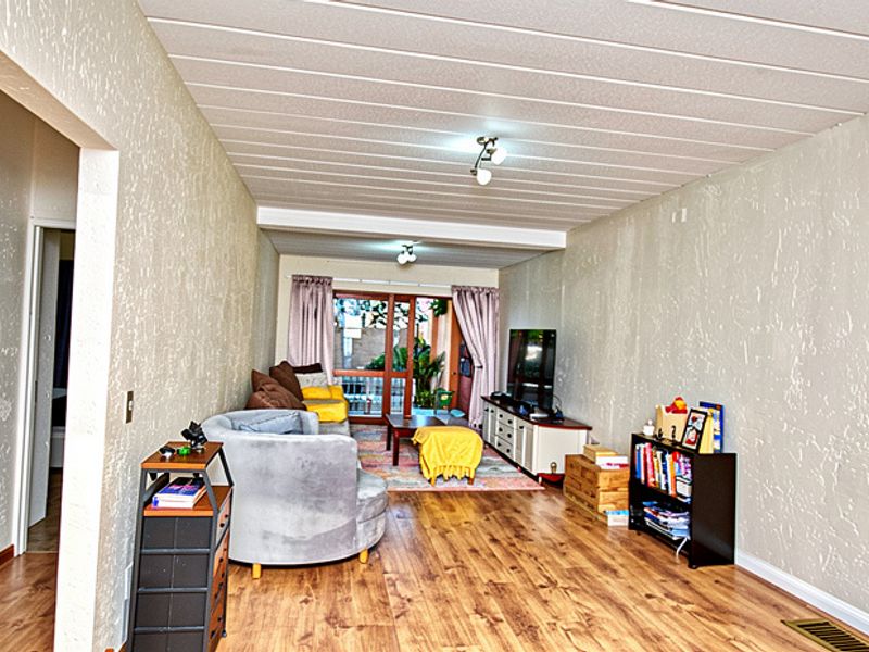 A living room featuring laminate flooring, textured walls, and a slatted ceiling, with a sliding glass door providing access to the outdoor area.