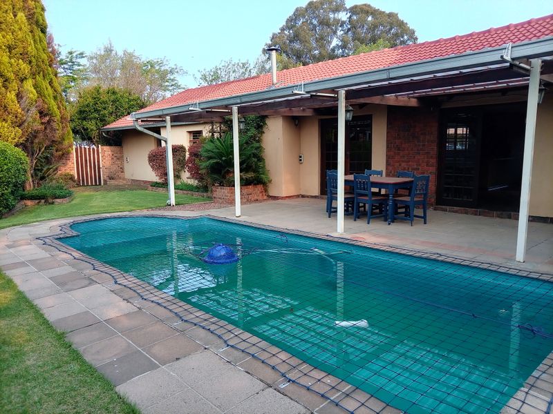 Outdoor entertainment area featuring a swimming pool with a safety net and a covered patio space adjacent to the main house structure.