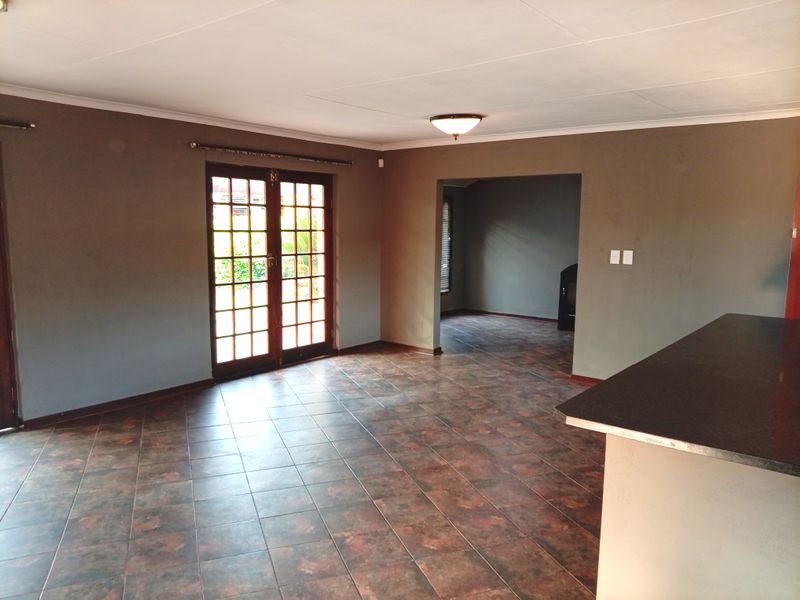 Spacious open-plan living area featuring tiled flooring, a breakfast counter, and double french doors leading to the exterior.