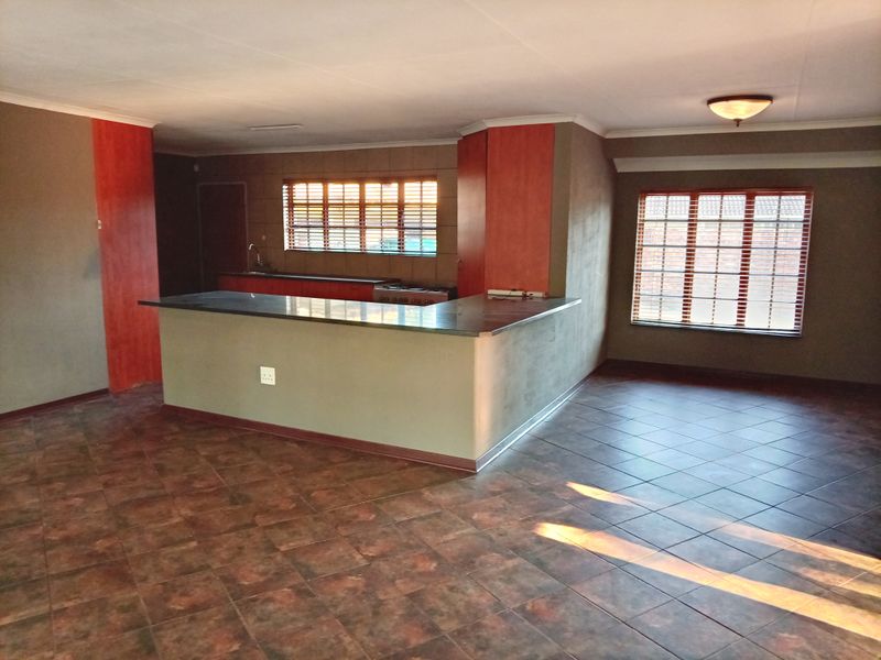 Spacious open-plan kitchen and living area featuring tiled flooring, a central island, and built-in cabinetry with ample natural light.