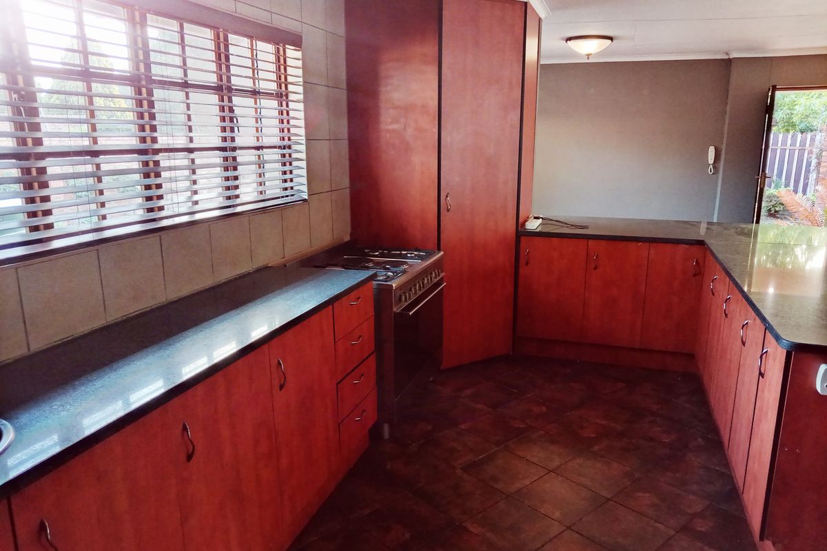 A functional kitchen featuring dark wood cabinetry, granite countertops, a gas stove, and tiled flooring, offering a clean and practical workspace.