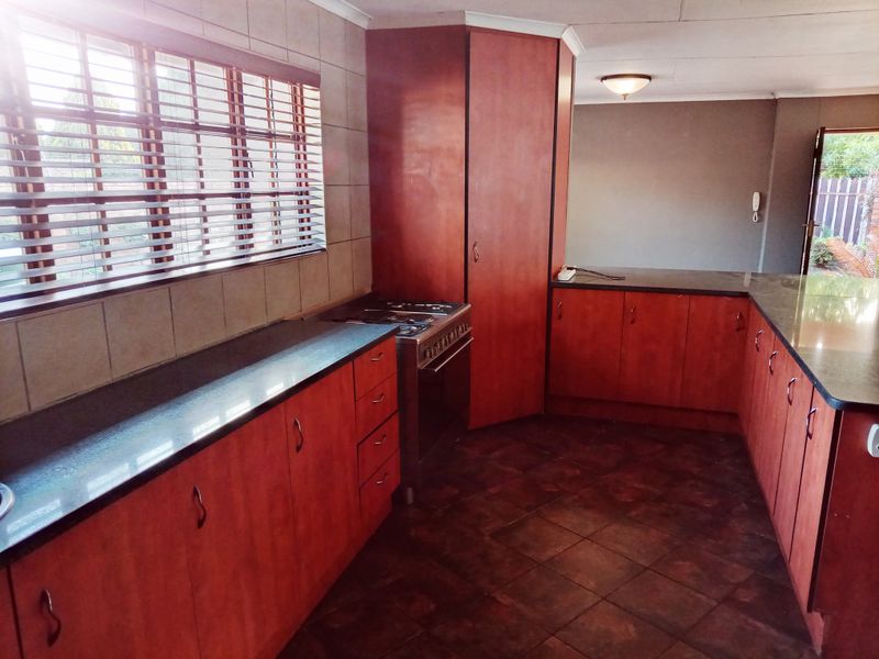 A functional kitchen featuring dark wood cabinetry, granite countertops, a gas stove, and tiled flooring, offering a clean and practical workspace.
