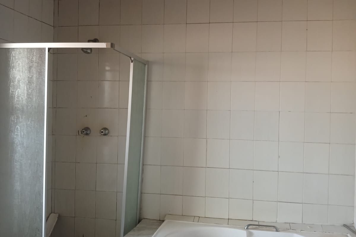 A dated bathroom featuring a built-in corner bathtub and a separate shower enclosure, requiring significant renovation and cosmetic updates to the ceiling and tiling.