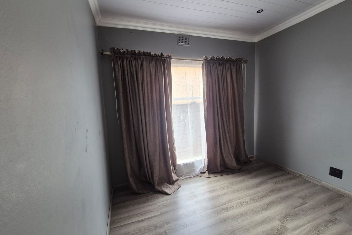 An empty bedroom featuring laminate flooring, a tongue and groove ceiling with recessed lighting, and neutral grey walls.